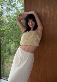 Top cropped crema con texture ondulata abbinato a pantaloni larghi di colore chiaro. Tessuto morbido, vestibilità comoda e vita con cordino.