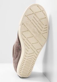 Calvin Klein Jeans Sneaker mit einem Obermaterial aus braunem Textil, weißer Gummisohle mit strukturiertem Profil und Logodetails auf der Unterseite.
