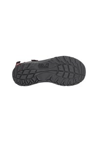 Black rubber sole of a Jack Wolfskin hiking sandal with deep tread patterns for traction on rugged terrain.