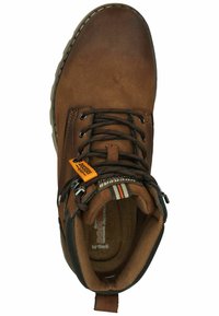 Botín de cuero marrón con cordones oscuros, etiqueta naranja, interior acolchado y acentos texturizados en negro. Punta redondeada y costuras reforzadas.