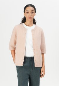 Light pink, knitted cardigan with a round neckline, three-quarter sleeves, and front button closure. Soft texture, paired with a white shirt.