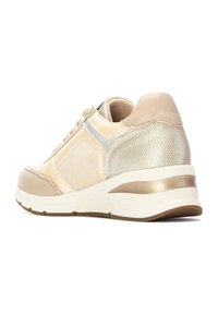 Sneaker beige con accenti metallici dorati, pelle e suede testurizzati, design con lacci, e una spessa suola bianca con una striscia dorata lungo il tallone.