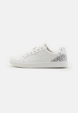 Witte lage sneaker met veters aan de voorkant, zilveren en glinsterend hieldetail, en geperforeerd zijlogo op een effen achtergrond.
