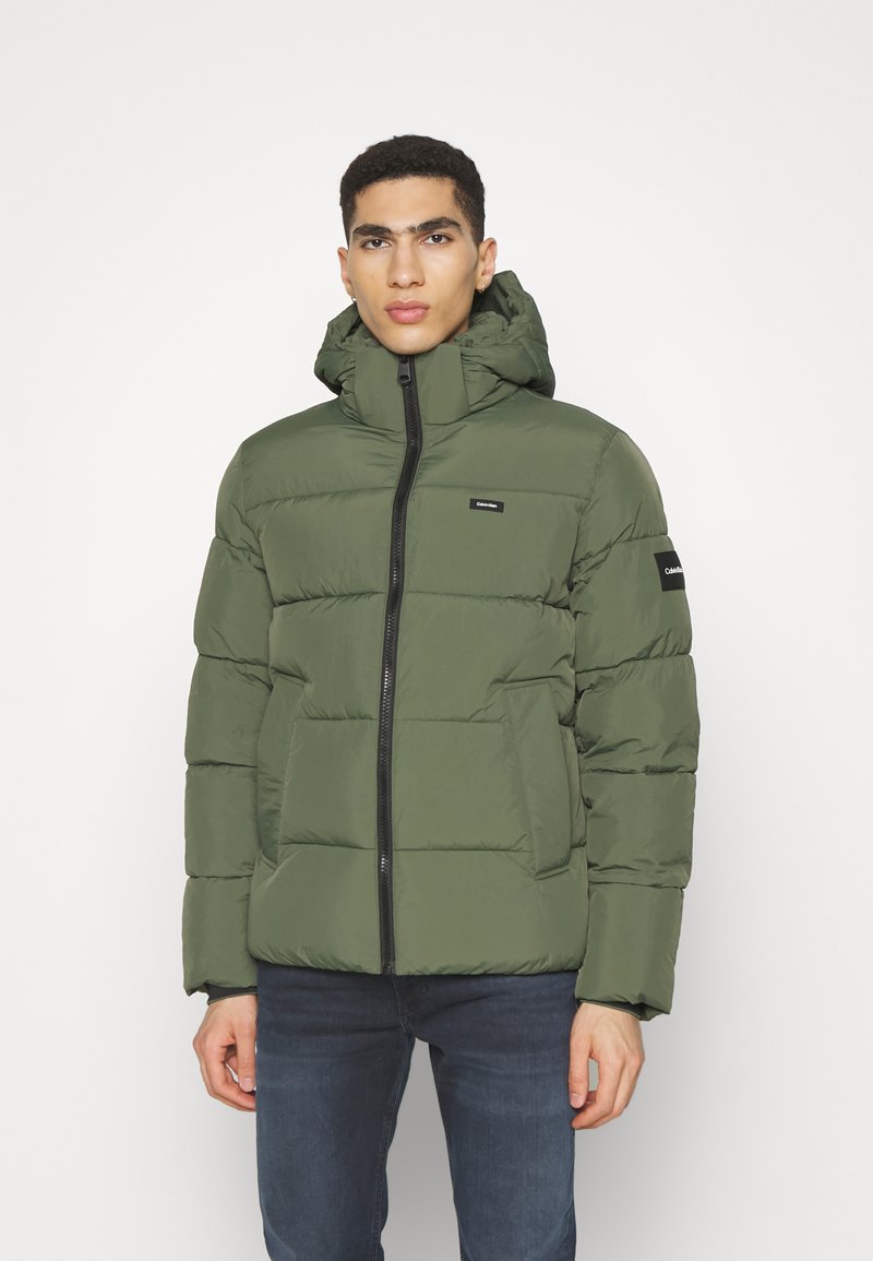 Giacca verde imbottita con chiusura a zip, cappuccio regolabile e dettagli neri. Presenta un design trapuntato e tasche frontali.