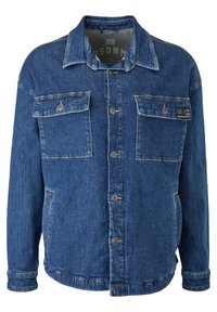 Chaqueta de mezclilla en azul medio con mangas largas, dos bolsillos en el pecho, cierres de botón y un corte relajado. Presenta costuras visibles y etiqueta de la marca.