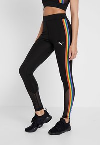 Leggings noirs avec des panneaux latéraux à rayures arc-en-ciel, présentant une texture lisse et une coupe ajustée. Logo Puma en blanc sur la cuisse gauche.