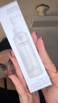 Bouteille transparente avec un bouchon pompe, enfermée dans une élégante boîte blanche. Présente un étiquetage minimaliste et une finition lisse et brillante.