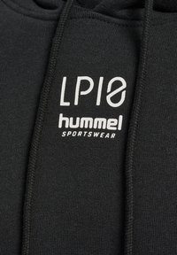 Svart hoodie med en mjuk textur, med vit tryckt logotyp "LP10 hummel SPORTSWEAR" och snördetalj vid huvan.