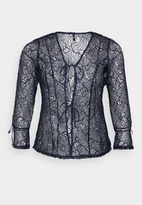 Blusa in pizzo blu navy con scollatura a V e maniche a tre quarti. Presenta dettagli con fiocco sul davanti e bordi scallop. Leggera e trasparente.