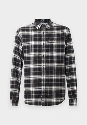 Chemise en flanelle à carreaux noir et blanc, à manches longues, avec un col à bouton, fermeture à boutons sur le devant et un petit logo sur la poitrine.