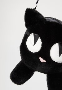 Borsa a forma di gatto nero in peluche con grandi occhi bianchi, dettagli sul musetto rosa, orecchie arrotondate e una cerniera nera. Include una tracolla a strisce.