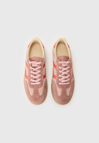 Pink suede sneakers with light pink laces and red side stripes. Features a rounded toe and a textured rubber sole.