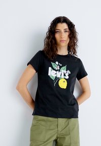 Černé bavlněné tričko s grafickým designem, na kterém je napsáno "levi's", žlutá citron a květinové akcenty. Přiléhavý střih, kulatý výstřih.