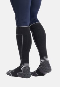 Calzini neri al ginocchio con accenti grigi e texture a coste. Punta e tallone rinforzati, progettati per comfort e supporto nell'uso atletico.