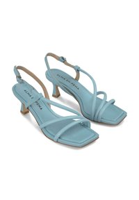 Helle blaue Riemchensandalen mit quadratischer Zehenpartie, mit einem Slingback-Design und einem kleinen Blockabsatz. Glatte Textur mit minimaler Verzierung.