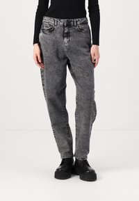 Γκρι τζιν παντελόνι με χαλαρή εφαρμογή, διαθέτει κλασικό σχέδιο πέντε τσεπών και διακριτική φθορά. Συνδυασμένο με μαύρες πλατφόρμες μποτάκια.