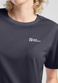 Donkergrijze T-shirt met een ronde hals, korte mouwen en een wit logo op de linkerborst. De stof lijkt glad met een subtiele textuur.