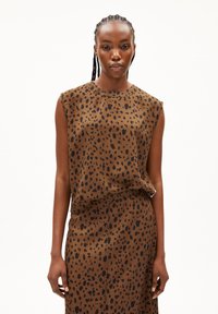 Brown sleeveless blouse with black leopard spots, featuring a loose fit and soft texture, paired with a matching skirt in the same pattern.