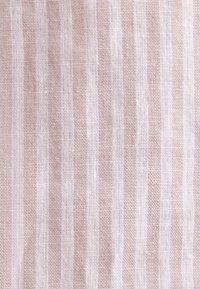 Tissu tissé rayé beige et blanc avec une surface texturée, légèrement rugueuse et un motif de tissage visible.