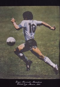En fodboldspiller i en hvid trøje med sorte shorts og nummer 10 løber og sparker en fodbold på græs.