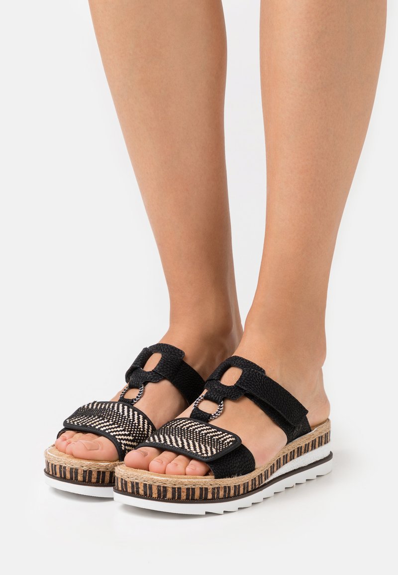 Sandales à plateforme noires avec un dessus en tissu tissé, des brides texturées et une semelle en liège rayée. Comprend deux brides réglables pour un bon ajustement.