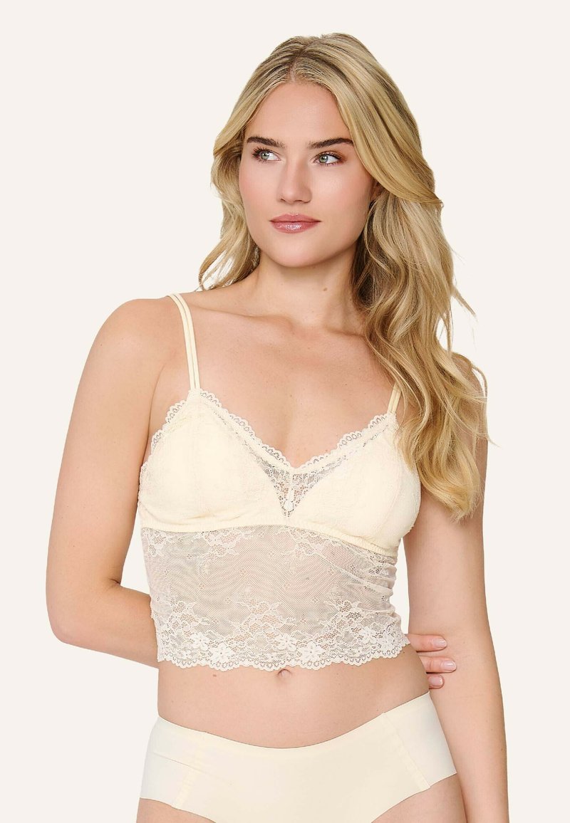 Crèmekleurige kant bralette met verstelbare bandjes, voorzien van een doorschijnend kanten paneel aan de onderkant, golvende randen en een V-vormige halslijn.