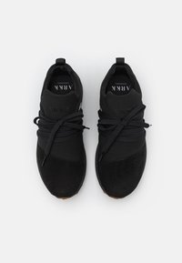 Czarne buty sportowe z gładką tkaninową cholewką z zamszowymi akcentami, zaokrąglonym noskiem i jednokolorowymi sznurowadłami, prezentujące minimalistyczne detale designu.