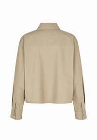 Chemise beige à manches longues avec poignets à boutons et col classique, vue de dos sur fond blanc.