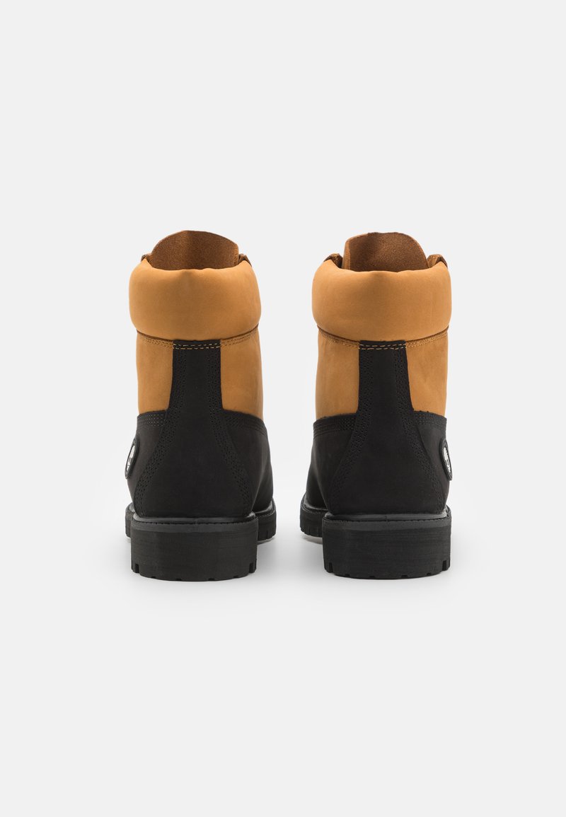 Bottines marron et noires en matériaux suédés et en cuir, avec un col haut, des coutures contrastées et une semelle en caoutchouc robuste.