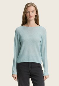 Pulover bleu deschis, realizat dintr-un material moale �și texturat; dispune de un guler larg și mâneci lungi, fiind asortat cu pantaloni închiși la culoare.