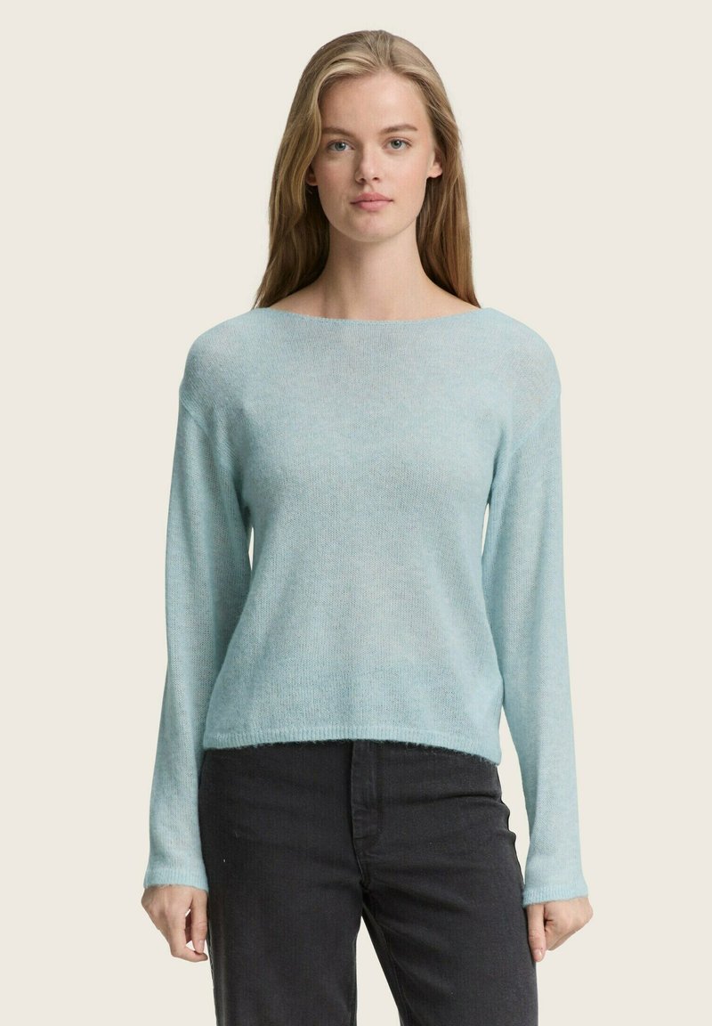 Pulover bleu deschis, realizat dintr-un material moale și texturat; dispune de un guler larg și mâneci lungi, fiind asortat cu pantaloni închiși la culoare.