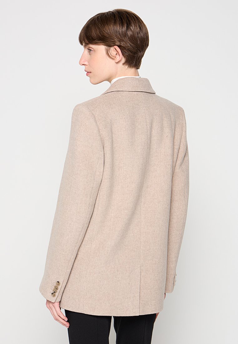 Beige Wollmischung-Blazer mit Reverskragen, einem hinteren Schlitz und Knopfmanschetten. Glatte Textur mit taillierter Passform und klaren Linien.