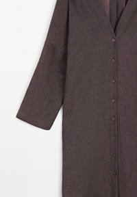 Dunkelbraunes Langarmkleidungsstück mitKnopfverschluss und V-Ausschnitt. Hergestellt aus strukturiertem Stoff mit einem lockeren, fließenden Design.