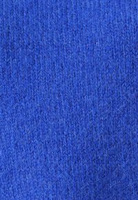 Nahaufnahme eines blauen, gestrickten Wollstoffs, der die detaillierte Textur und die einzelnen Garnfasern zeigt.
