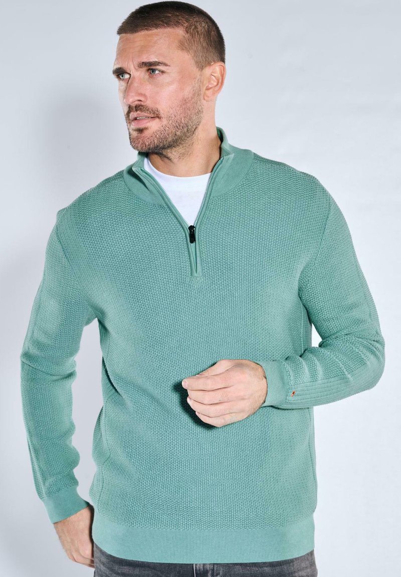 Hellgrüner Reißverschluss-Pullover mit strukturiertem Muster und langen Ärmeln, ausgestattet mit hohem Kragen und gerippten Bündchen.