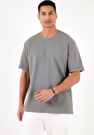 Grå t-shirt med korte ærmer, ribbet tekstur, rund halsudskæring og oprullede manchetter, med en afslappet pasform og sideslids.