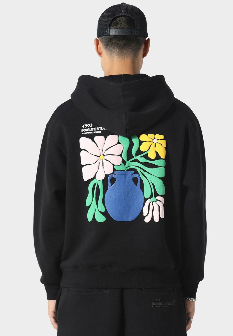 Mustat hupparit, joissa on suuri, värikäs kukkakuva, jossa on sininen maljakko, vaaleanpunaisia ja keltaisia kukkia sekä vihreitä lehtiä takana.