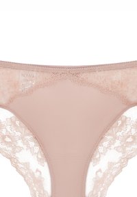 Nudefarbener Spitzen-String mit einer glatten Frontpartie und Spitzenbesatz an den Seiten. Weicher Stoff mit floralem Spitzenmuster für zusätzliche Details.