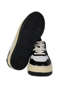 Sneaker basse in bianco e nero con tomaia in pelle liscia, punta texturizzata, dettagli perforati e suola in gomma spessa.