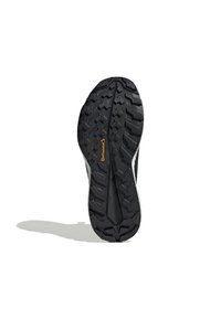 Black rubber shoe sole with deep treads, featuring a textured surface and a prominent Continental logo in orange near the center.