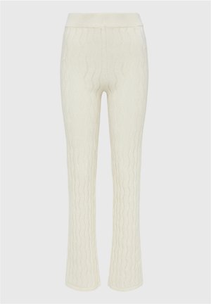 Pantalons blancs en tricot à cable avec une taille côtelée, des jambes évasées et un motif texturé en vagues sur l'ensemble du tissu.