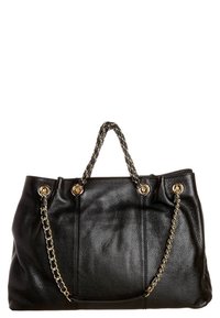 Černá texturovaná kožená kabelka se zlatými řetízkovými uchy a zlatými nýty na bílém pozadí.