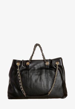 Černá texturovaná kožená kabelka se zlatými řetízkovými uchy a zlatými nýty na bílém pozadí.