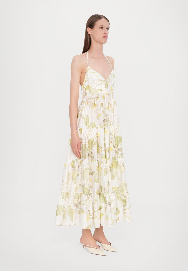 Vestido maxi de tela blanca con estampado botánico verde, con escote en V, tirantes finos, diseño en capas y una silueta fluida.