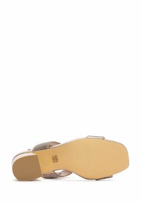 Sandale ouverte avec une tige métallique texturée dans une teinte beige-or. Elle présente une semelle robuste avec des motifs de traction et un talon décoratif.
