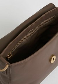 Brun læderhandbag med en lynlåslomme og gyldent hardware. Interiøret har en glat stofforing og minimalistisk design.