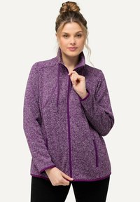 Giacca in pile viola con chiusura a zip, colletto alto, cordini regolabili e rifiniture a contrasto. Presenta tasche laterali e un tessuto testurizzato.