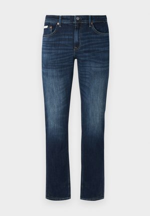 Jeans de denim azul oscuro con un corte de pierna recta, que presentan un diseño clásico de cinco bolsillos, herrajes de cobre y sutiles detalles de desgaste.