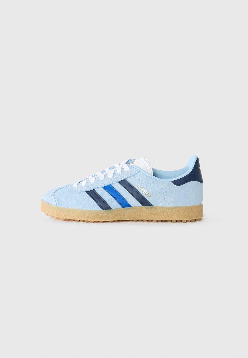 Lyseblå semsket sko med tre vertikale striper i mørkeblå og svart, hvite snøringer og såle i gummi. "Gazelle" er trykt i gull.