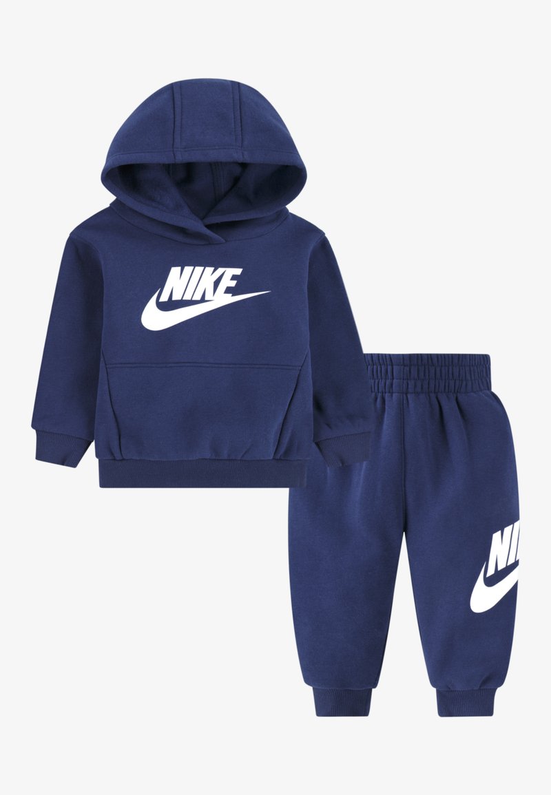 Set din bumbac albastru închis format din hanorac cu glugă și pantaloni sport cu logo Nike alb. Include o glugă, manșete striate și talie elastică pentru confort.